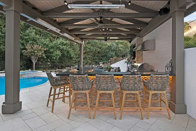 Outdoor pavilion bar in Danville, CA with timber roof, woven bar stools and a pool beyond