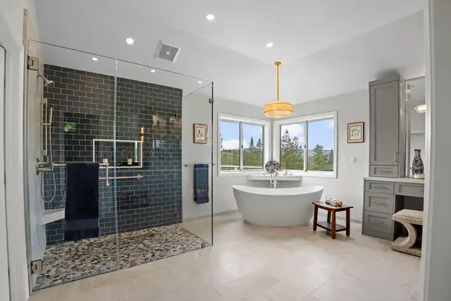 Diablo, CA primary bathroom with a navy tile walk-in shower, a freestanding tub and a pendant light